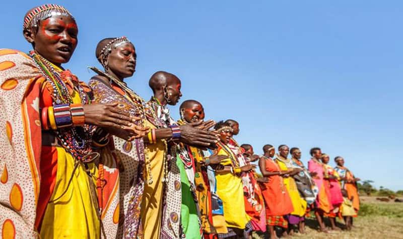 Grupo de mulheres Massai alinhadas no deserto com vestidos coloridos